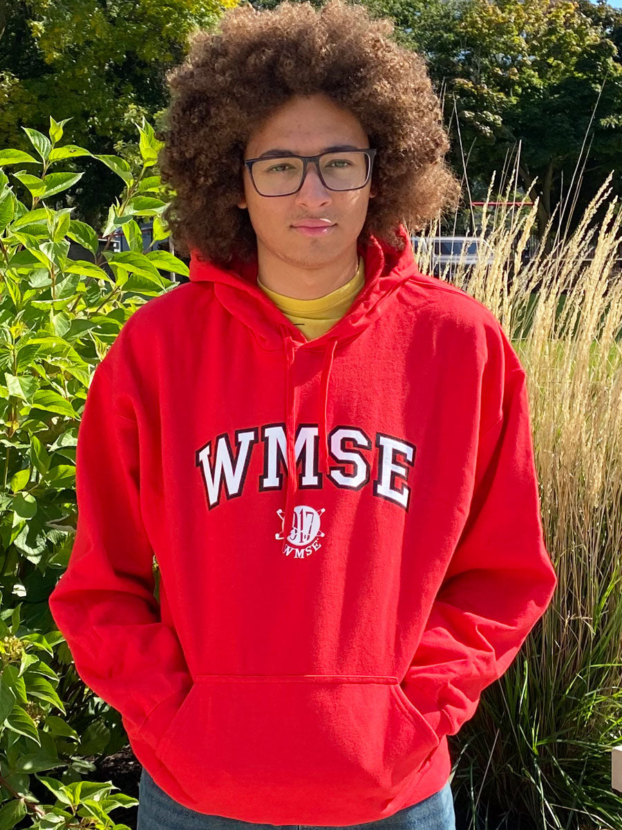 Jackson wearing a red hoodie with 'WMSE' printed on it, standing outdoors among greenery.