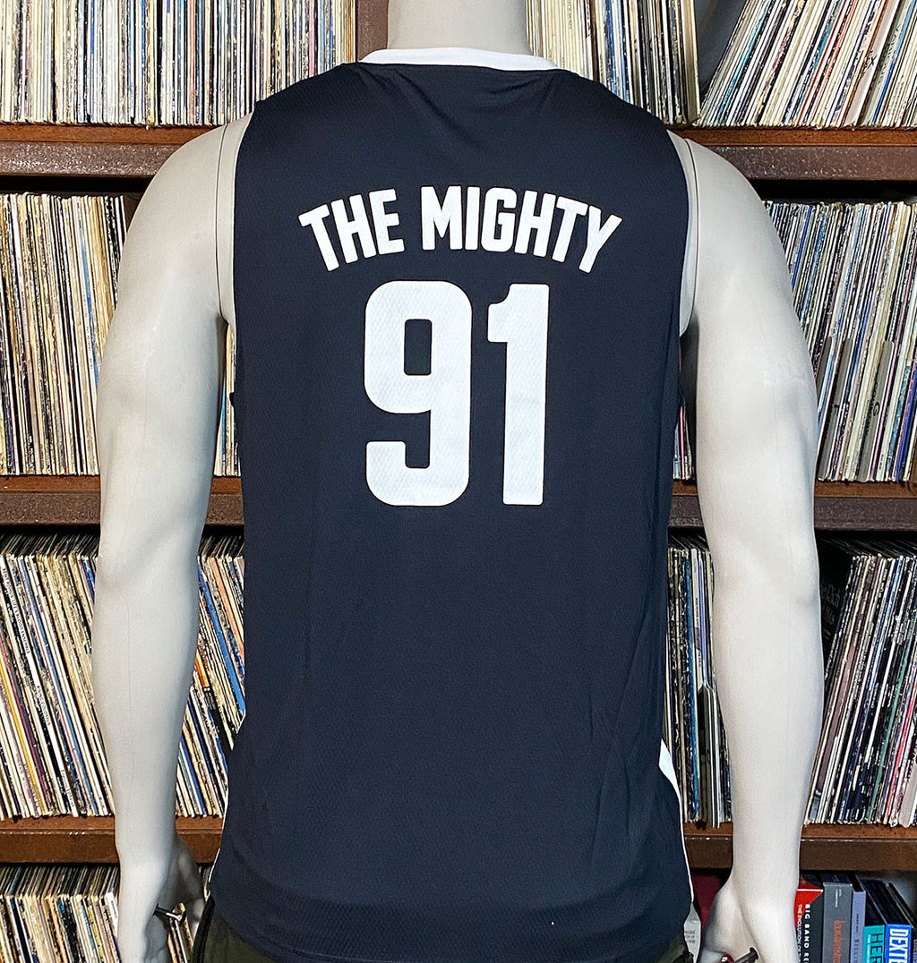 Black sleeveless shirt with 'THE MIGHTY 91' text on a mannequin against a bookshelf background