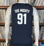 Black sleeveless shirt with 'THE MIGHTY 91' text on a mannequin against a bookshelf background
