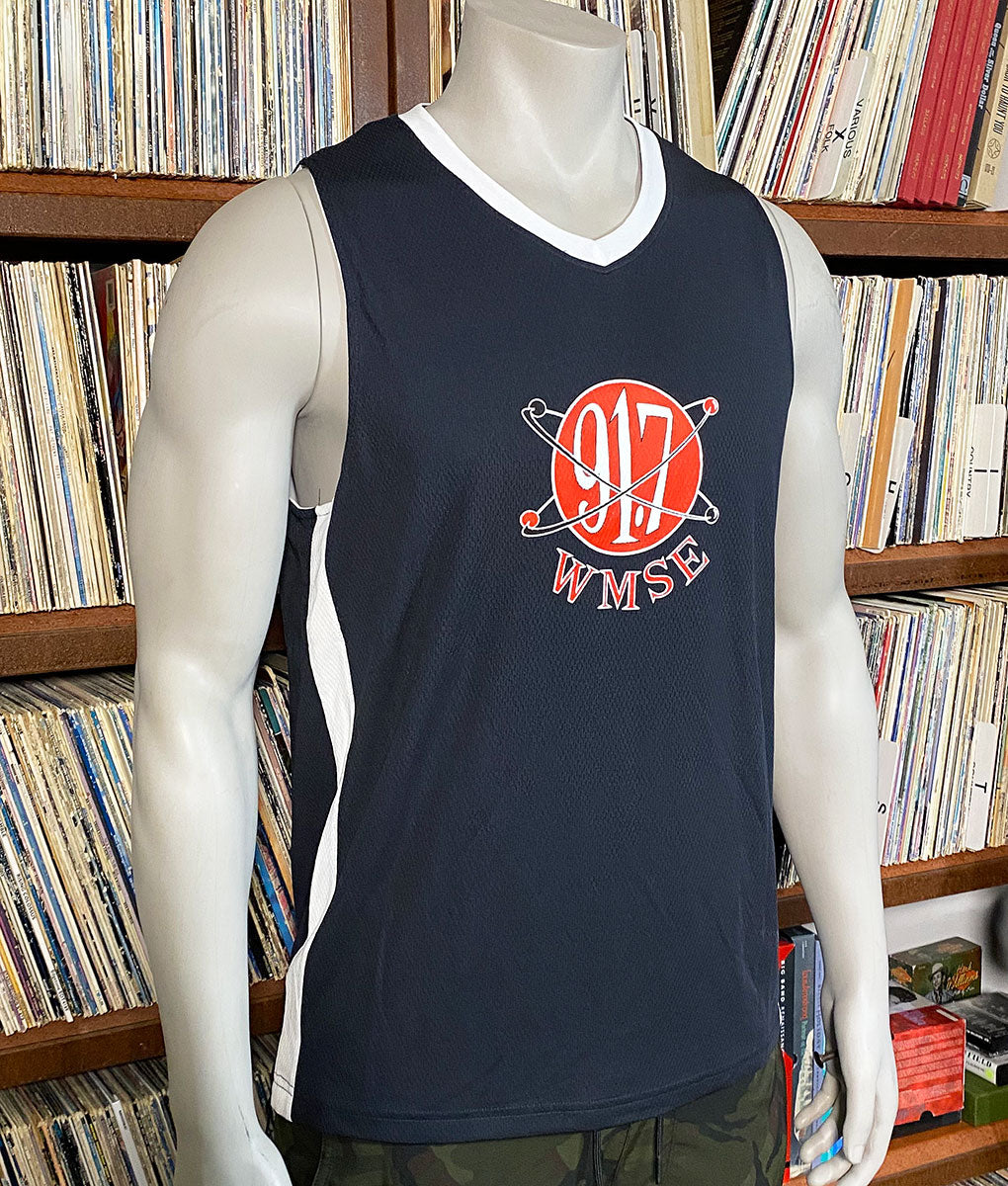Black sleeveless shirt with red and white logo on a mannequin in front of a bookshelf.