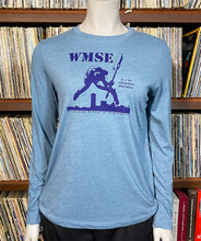 Load image into Gallery viewer, Blue long-sleeve shirt with graphic design on a mannequin against a bookshelf background